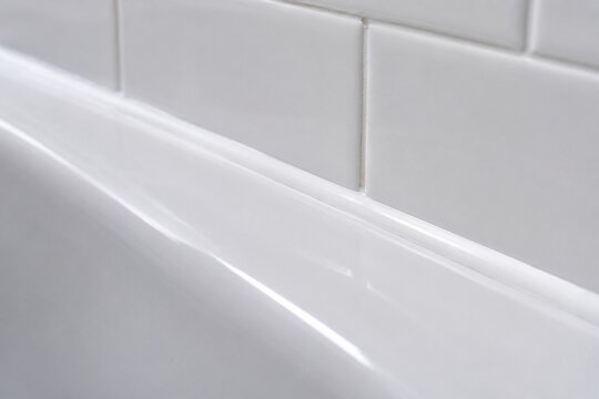 A smooth, continuous bead of white sealant along a bathtub and tile joint.