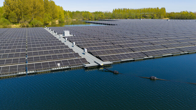 Aerial view of a large floating solar farm on a lake surrounded by lush green trees in Zwolle, Overijssel, Netherlands.