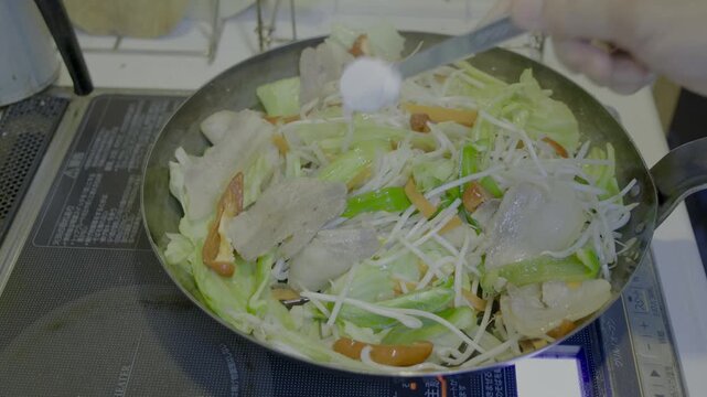 鉄フライパンを用い、肉野菜炒めを調理中、塩を入れ混ぜ合わせ、フライパンを振るシーン　56秒