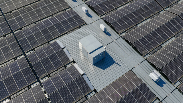 Aerial view of a large solar panel array with rows of photovoltaic panels and central electrical equipment in Zwolle, Overijssel, Netherlands.