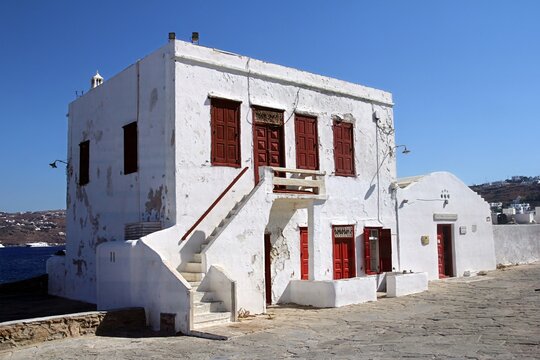 Traditional Cycladic white house with red doors and windows in Mykonos, Greece