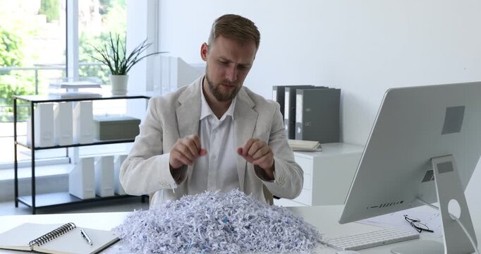 Man with shredded paper pieces at table in office