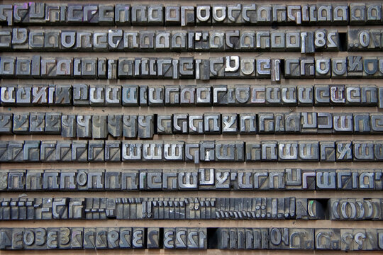 Collection of traditional letterpress printing equipment, metal type, wooden letters and vintage typography tools used in historical printing and typesetting.