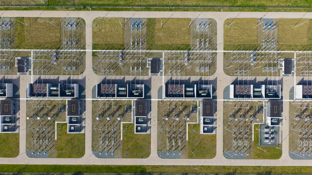 Aerial view of an electrical substation with rows of transformers, switchgear, and power lines arranged in a grid pattern on a grassy site in Velsen-Noord, North Holland, Netherlands.