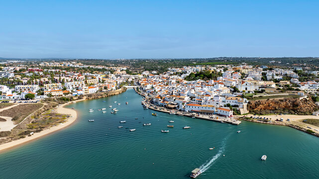 Aerial view of the coastal town with its white buildings, boats on the river Arade, and sandy beaches in Ferragudo, Faro District, Portugal.