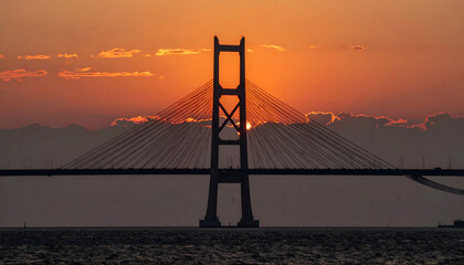 Obraz premium Iconic Suspension Bridge Tower Silhouetted Against Dramatic Sunset Sky.