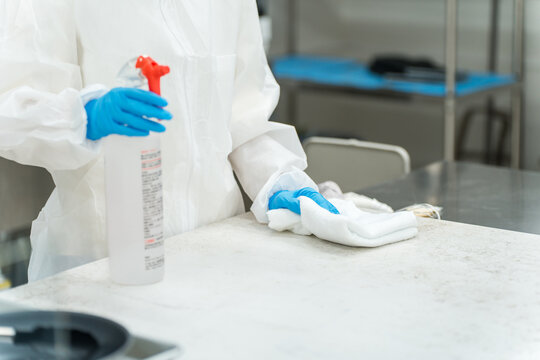 Cleaning and specialized cleaning workers (men and women) who wear dustproof suits and cleanroom wear to perform disinfection cleaning (hygiene management, cleanroom)