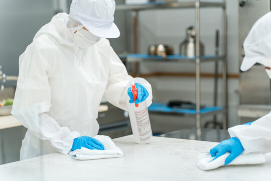 Cleaning and specialized cleaning workers (men and women) who wear dustproof suits and cleanroom wear to perform disinfection cleaning (hygiene management, cleanroom)