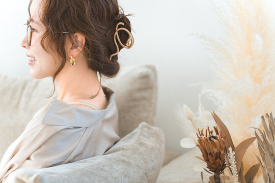 A profile view of a stylish Asian woman relaxing on a living room sofa.
