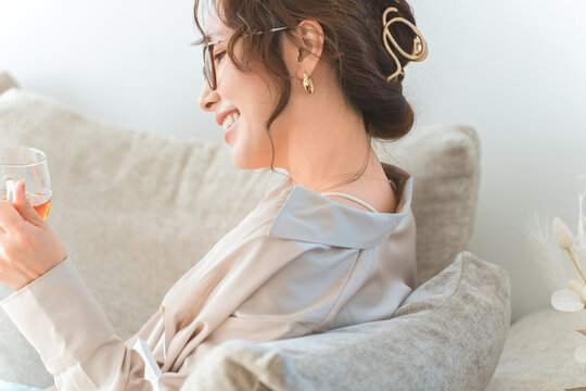 A stylish Asian woman relaxing on a living room sofa during teatime.