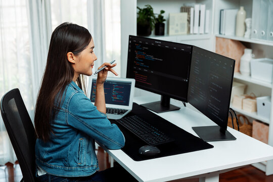 Young Asian IT developer looking online information on pc for beautiful pose with coding program data of website application, wearing jeans shirt. surround by safety analysis two screens. Stratagem.