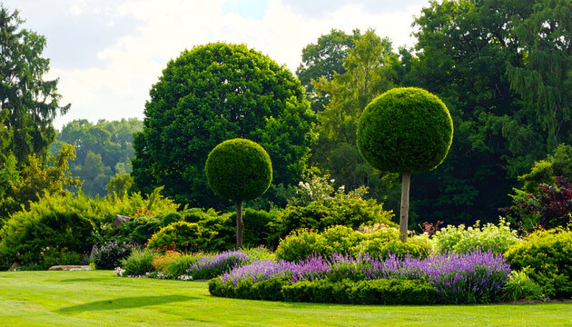 Beautifully manicured garden with spherical topiary trees and colorful flower beds.