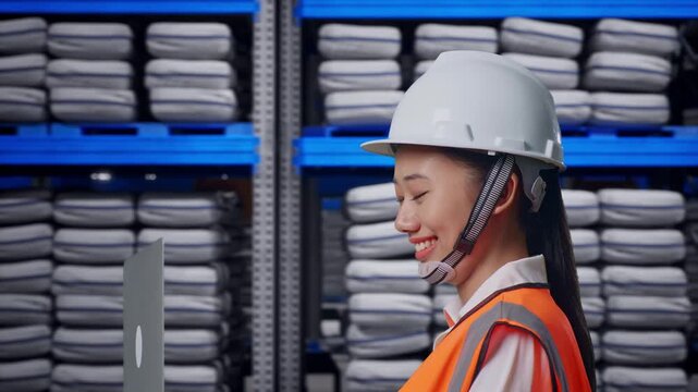 Side View of Asian Female Engineer Use Computer While Walking at Warehouse storage with stacked white sacks