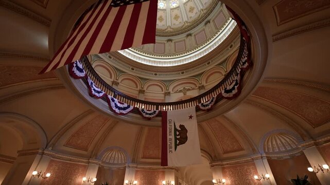 Look up at the dome and rotunda of the California State Capitol in Sacramento showing flags and patterns.