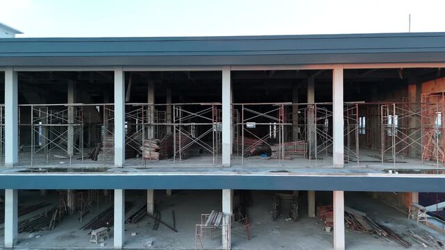 An unfinished commercial concrete building, currently under construction, equipped with scaffolding and unfinished floors.