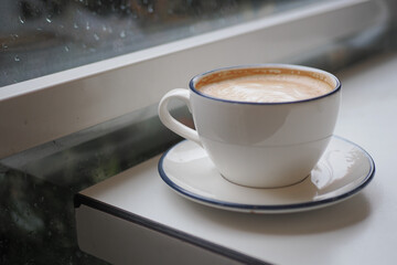 Naklejka premium Coffee cup sits on table near window during rainy day
