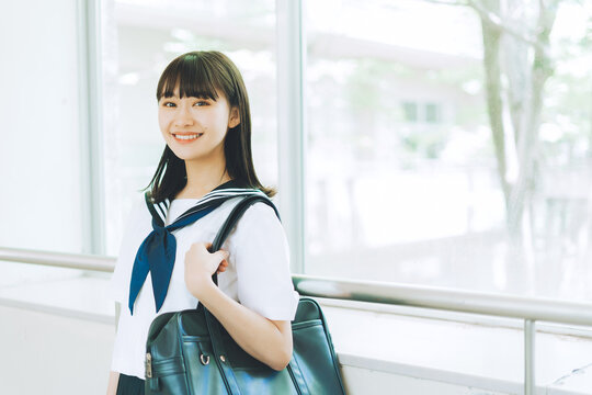 学校の廊下を歩く夏服の女子高校生