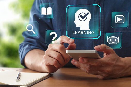 Mobile learning and e-learning application supporting employee training and professional skill development remotely. Man using smartphone at table.