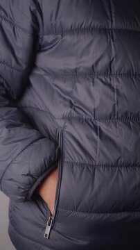 Person Putting Hand Into Pocket of Puffer Jacket