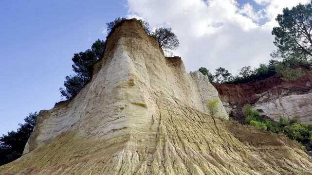 Low-angle view up a towering pale ochre and kaolin cliff pinnacle