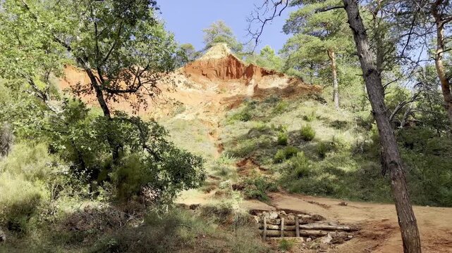 A red ochre pinnacle rising above a sandy woodland trail