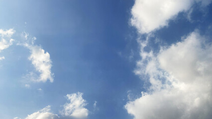 Fototapeta premium Clear blue sky background with scattered fluffy white clouds