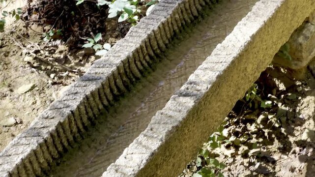 Old stone water channel with a mineral-encrusted trough carrying