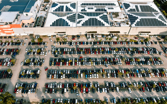 Iloilo City, Western Visayas, Philippines - 01 July 2026: Aerial view of a large commercial building with extensive rooftop solar panels and a crowded parking lot filled with vehicles.