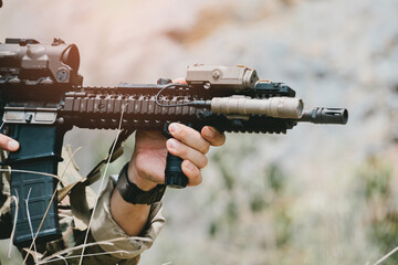 Fototapeta premium Outdoor military concept. Firearm close up tactical weapon soldier hand aiming combat military scope barrel grip outdoor training weapon rifle