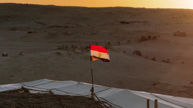 Egyptian Flag Waving over Bedouin Desert Camp at Sunset with Sandy Dunes in Background in Ras Muhammad