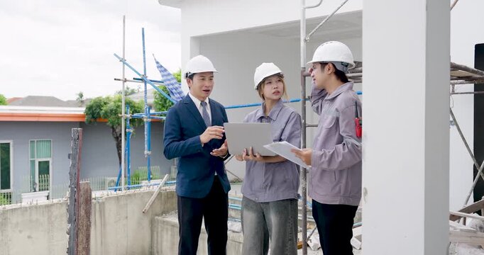 Asian female engineer holds blueprint beside male manager and contractor during building inspection, reviewing construction work plan, safety compliance, document checking, and project progress.