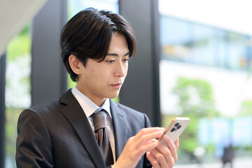 スマートフォンを操作するアジア人ビジネスマン © mapo