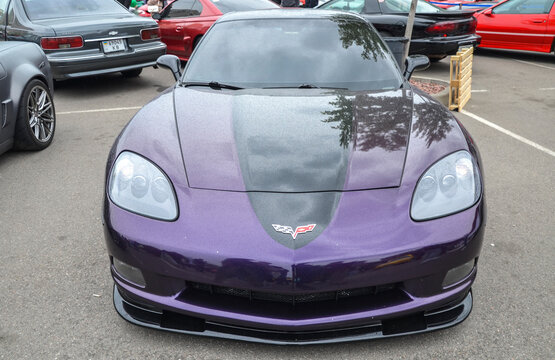Eye catching vehicle is a Chevrolet Corvette C6 Coupe, sporting a unique deep purple paint finish accented by a contrasting dark metallic center strip down the hood
