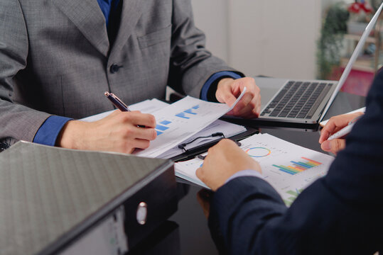 businessmen writing clipboard reviewing financial bar charts documents office desk corporate managers analyzing business data performance metrics accounting auditing paperwork planning investment