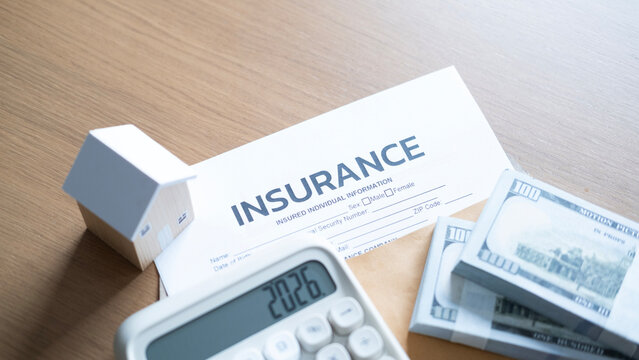 Mortgage insurance and housing budget concept with wooden house model, calculator, insurance form, cash bundles, and envelope.