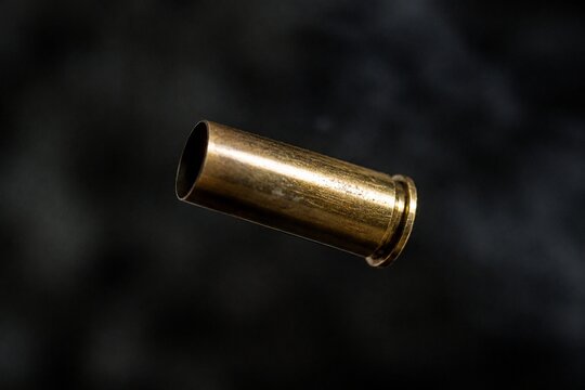 Single brass cartridge case ejected from an antique revolver, isolated on dark background.
