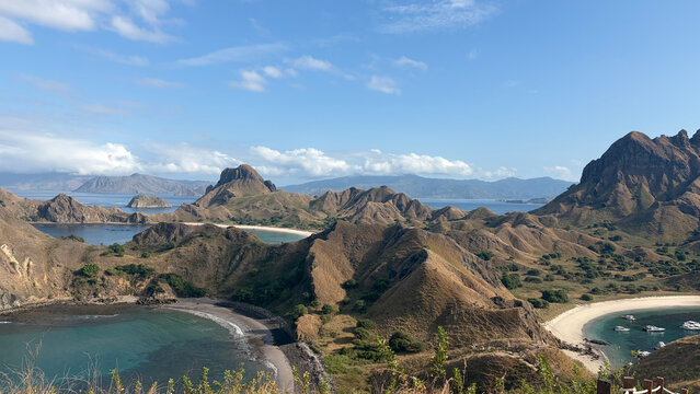 Panoramic view of Padar Island in Komodo National Park, Indonesia, showcasing multiple bays, rugged hills, and a clear blue sky.