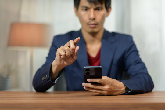 Young man using smartphone with focused expression indoors at home