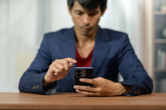 Businessman Using Smartphone at Desk in Modern Office Environment