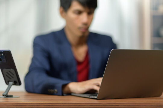 Businessman Working on Laptop at Desk in Modern Office Environment