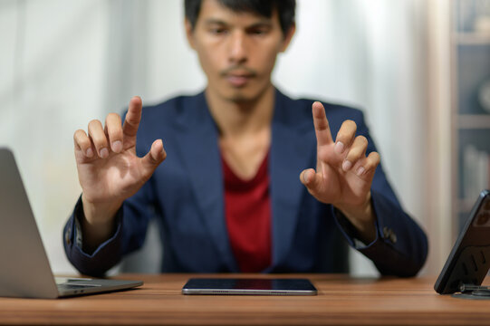 Businessman Demonstrating Gesture with Hands at Desk in Modern Office