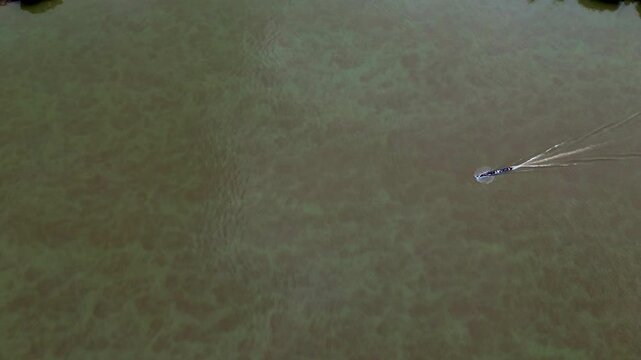 Top Down Drone View of Small Motorboat on Wide Muddy River in Ecuador, Brown Water Texture, Wake Lines and Remote Amazon Transport Scene