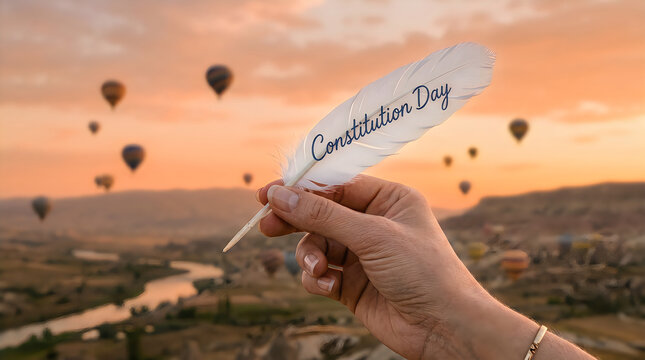 Hand holding a white feather pen for constitution day