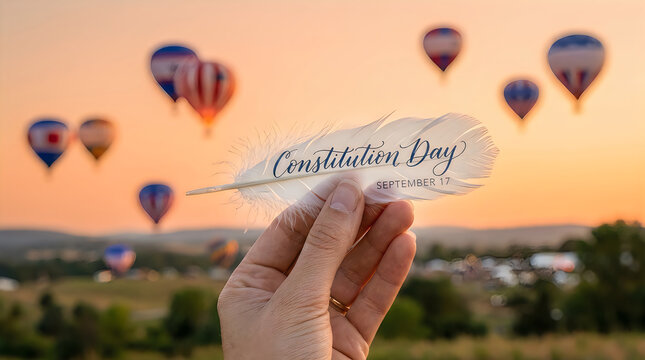 Constitution day note held in hand with hot air balloons