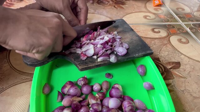 Close up hands slicing red shallots on wooden cutting board