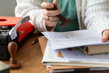 Fototapeta na wymiar Person stamping documents at a desk with a typewriter and papers.