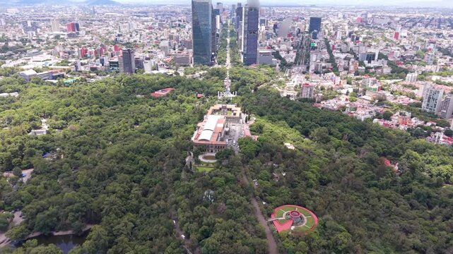 Aerial view of Chapultepec Castle and Mexico City skyline. Drone shot of historic castle, lush green park and skyscrapers on Paseo de la Reforma in CDMX.