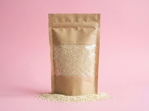 Quinoa grains in a resealable kraft pouch against a vibrant pink background with subtle studio lighting