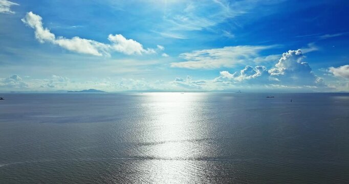 Aerial view of bright sunlight reflecting on the calm sea surface under a blue sky in Zhuhai, China
