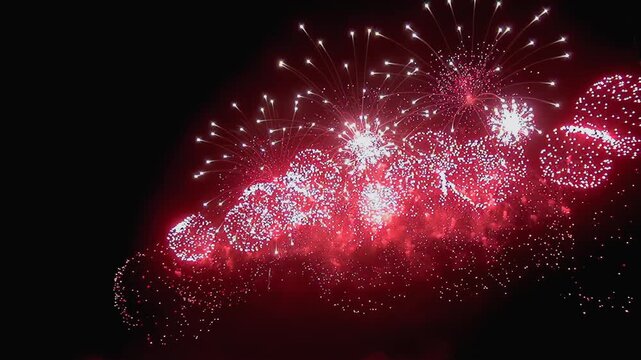A late-night celebration unfolds as crimson fireworks erupt across the dark sky. Explosions of light paint the darkness, creating a dazzling and vibrant experience.